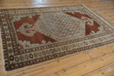 Malayer rug corner with worn geometric borders and tattered fringe detail.