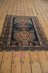 A vintage Persian Malayer rug with triple oversize medallions seen from a long, angled perspective.