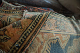 Distressed vintage Malayer rug showing dark green selvage, geometric border, and visible knot heads.