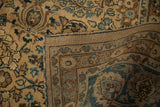 Close-up of distressed vintage Meshed rug with camel and blue floral motifs, revealing woven foundation.