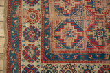 Antique Caucasian rug showing geometric field patterns, sapphire blue border, and natural aged wear.