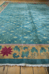 Dusty ocean teal Art Deco carpet with gold border, raspberry red flower, and fringe.