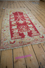Distressed vintage Oushak rug featuring cherry red prayer motif with lantern and ivory vines.