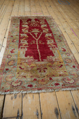 Vintage distressed Oushak rug corner with faded raspberry floral vines and sea foam border.