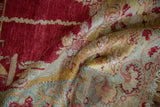 Faded raspberry, gold, and sea foam vine patterns on a curled distressed Oushak rug.