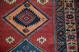 Serrated tangerine diamond medallion, navy accents, and geometric crab style border of vintage Persian runner.