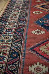 Serrated diamond medallions on cochineal red field and navy geometric border detail.