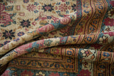 Folded antique Kerman runner revealing intricate border with pale copper, cochineal, and powder blue motifs.