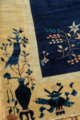 Cobalt blue pictorial vase and floral vinery on dusty gold border of vintage Chinese carpet.