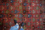 Antique Caucasian rug detail: dusty raspberry field, hand-knotted staggered floral lattice, abrashes.