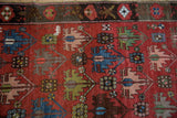 Staggered geometric floral motifs and abrashes on antique Caucasian carpet.