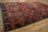 Antique Caucasian rug's lattice of staggered floral, pinwheel motifs in raspberry, indigo, and green.