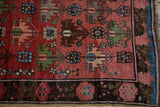 Hand-knotted antique Caucasian rug: dusty raspberry geometric field, dark border, blue selvage.