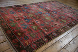 Antique Caucasian rug corner: dusty raspberry field, floral lattice, dark aubergine border, and fringes.