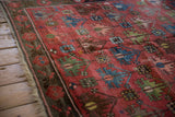 Antique Caucasian rug's lattice pattern of floral blossoms, pinwheels, and raspberry abrashes.