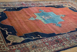 Elongated Samovar design in indigo blue borders the abrashed madder red field.