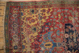 Fringe, green minor border, saffron spandrel, navy blue medallion on worn cherry red field.