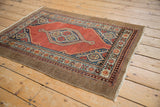 Angled perspective on a vintage Serab rug, showing its brick red medallion and natural camel border.