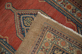 A folded corner reveals the camel hair foundation and hand-knotted brick red pile of a vintage Serab rug.