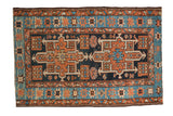 Vintage Karaja rug with double geometric medallion, floral field, and patterned border in navy, terracotta, sky blue.