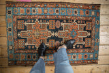Vintage Karaja rug with geometric medallion, starburst border, and edge wear; terracotta, navy, sky blue.