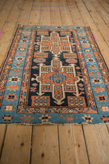 Angled detail of Karaja rug's sky blue starburst border, terracotta geometric motifs, and abrashes.