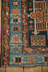 Detail of Karaja rug's starburst floral border in sky blue and terracotta, beside geometric motifs.