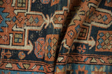 Folded detail of geometric relief patterns in pale terracotta, dusty navy, and sky blue abrashes.