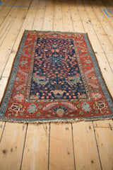 Vintage Hamadan rug corner: red border with expressive floral motifs, navy field, tattered ends.