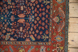 Vintage Hamadan rug detail: navy millefleur field, red border with serrated leaves, frayed edge.