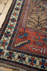 Kurdish Hamadan rug corner with geometric floral border in beige, red, and dusty teal hues.