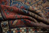 Folded vintage Hamadan rug, showing geometric patterns in camel, brick red, and dusty teal.