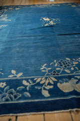 Hand-knotted vintage Peking carpet: indigo blue field, ivory eucalyptus vinery, and worn texture.