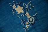 Vase and ivory blossoms detail with blue leaves on a vintage Peking carpet's indigo field.
