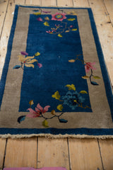 Art Deco rug close-up: blush blossom, lime vinery on sapphire blue field, oxidized silver border.