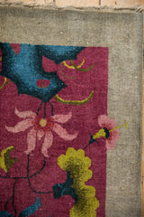 Art Deco rug corner with expressive pink blossoms, lime green vinery on burgundy, and beige border.