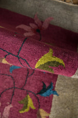 Curled edge of Vintage Chinese Art Deco rug with burgundy pile and floral vinery.