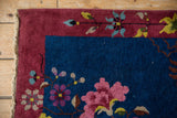 Nichols Art Deco rug corner: indigo blue field, burgundy border, expressive pink and blue blossoms, original selvage.