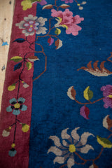 Nichols Art Deco rug with sprawling floral vines on indigo blue, dusty raspberry border.