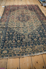 Senneh rug showing navy Herati motifs, inverted ivory ground, floral geometric border, tattered fringe.