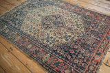 Antique Senneh rug's tomato red finned border, navy Herati field, and tattered edges.