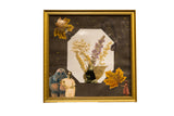 The Wildflower & The Golem mixed media art in a gold frame, with a collage of dried flowers and vintage photos.