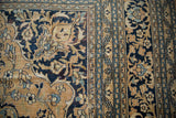 Gold and navy blue scrolling blossoms with even wear on a vintage Doroksh rug's patterned border.