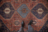 Vintage Qashqai rug featuring a geometric medallion and tribal motifs in madder red and navy.