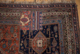Vintage Qashqai carpet's large patch joining madder root red and navy tribal fields.