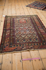 Worn ruby red geometric serpent border and pinwheel floral motif on an antique Daghestan rug.