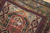 Antique Daghestan geometric field motifs, ruby red, navy blue, and ivory wear.