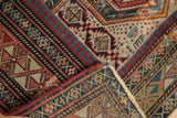 Daghestan rug corner with geometric ruby red, navy patterns, machine-bound side, and fringe.