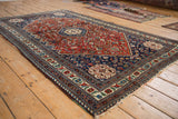 Angled view showing the serrated hexagonal medallion and detailed red field of a vintage Abadeh rug.