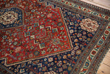 Hand-knotted texture of a fine Abadeh rug's corner, showing deep red and blue geometric patterns.